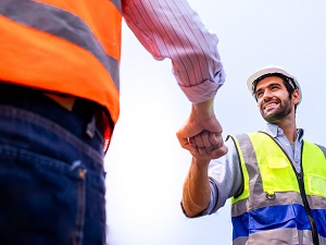 Two construction workers doing a fist pump indicating they are happy.