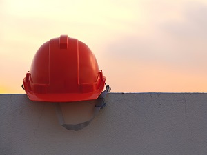 A red hard hat sitting on a gray wall with a hazy sky in the background.
