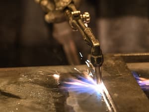 Close-up of a cutting torch in use, creating a focused flame on a metal surface.