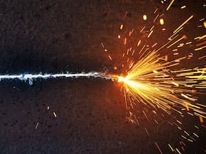 Horizontal line of intense sparks and flame from a metal cutting process.