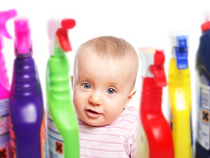 A cute baby with some household chemical bottles
