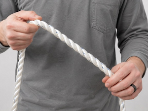 Worker performing a pre-use inspection of a rope fall protection lanyard by examining its full length.