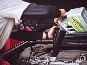 Mechanic pouring engine oil into a vehicle during routine automotive maintenance