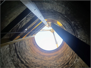 View from inside a vertical confined space showing a ladder and access opening above.