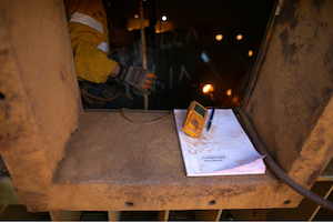 Portable gas monitor and confined space entry permit positioned at the opening of an industrial confined space.