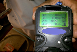 Close-up of a four-gas monitor displaying readings for oxygen, carbon monoxide, hydrogen sulfide, and combustible gases.