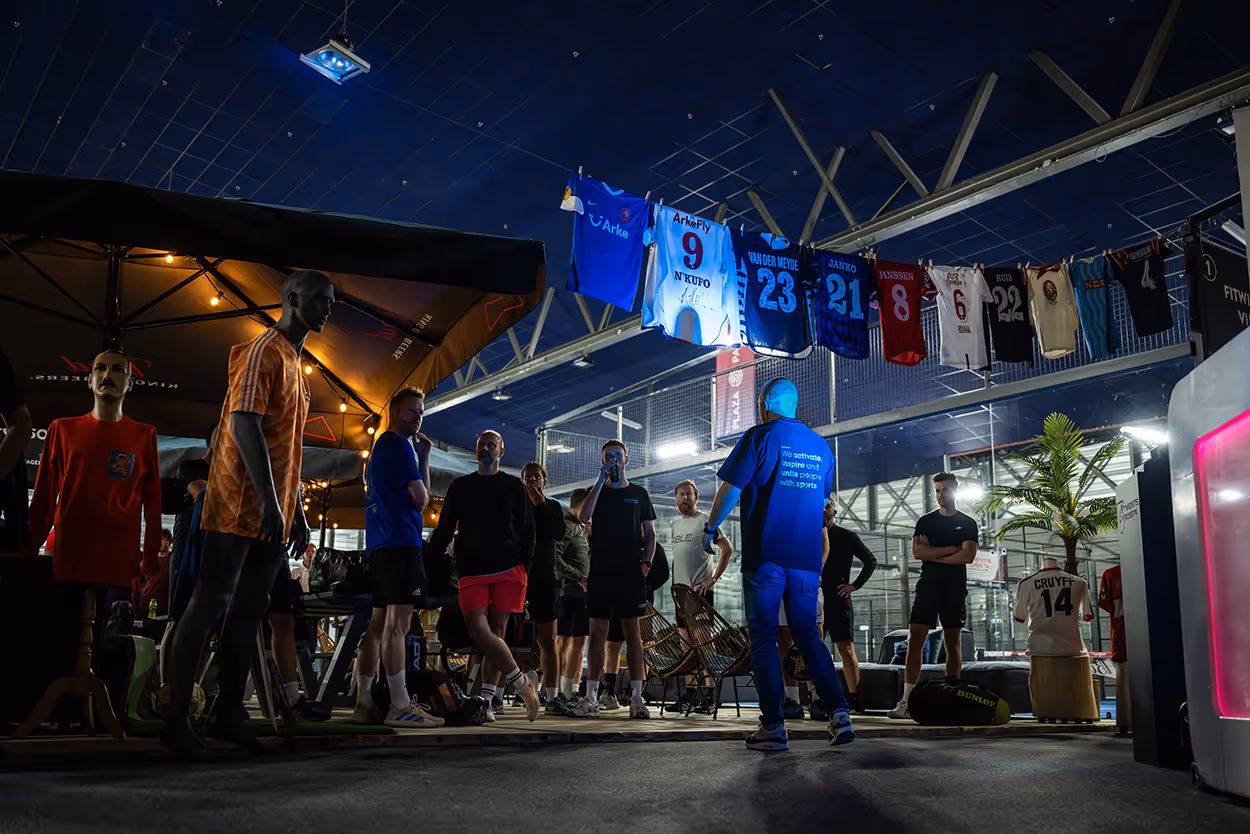 De oprichter van sportmarketingbureau FrontRow is tijdens een B2B sportevenement aan het spreken op de padelbaan omringd door deelnemers