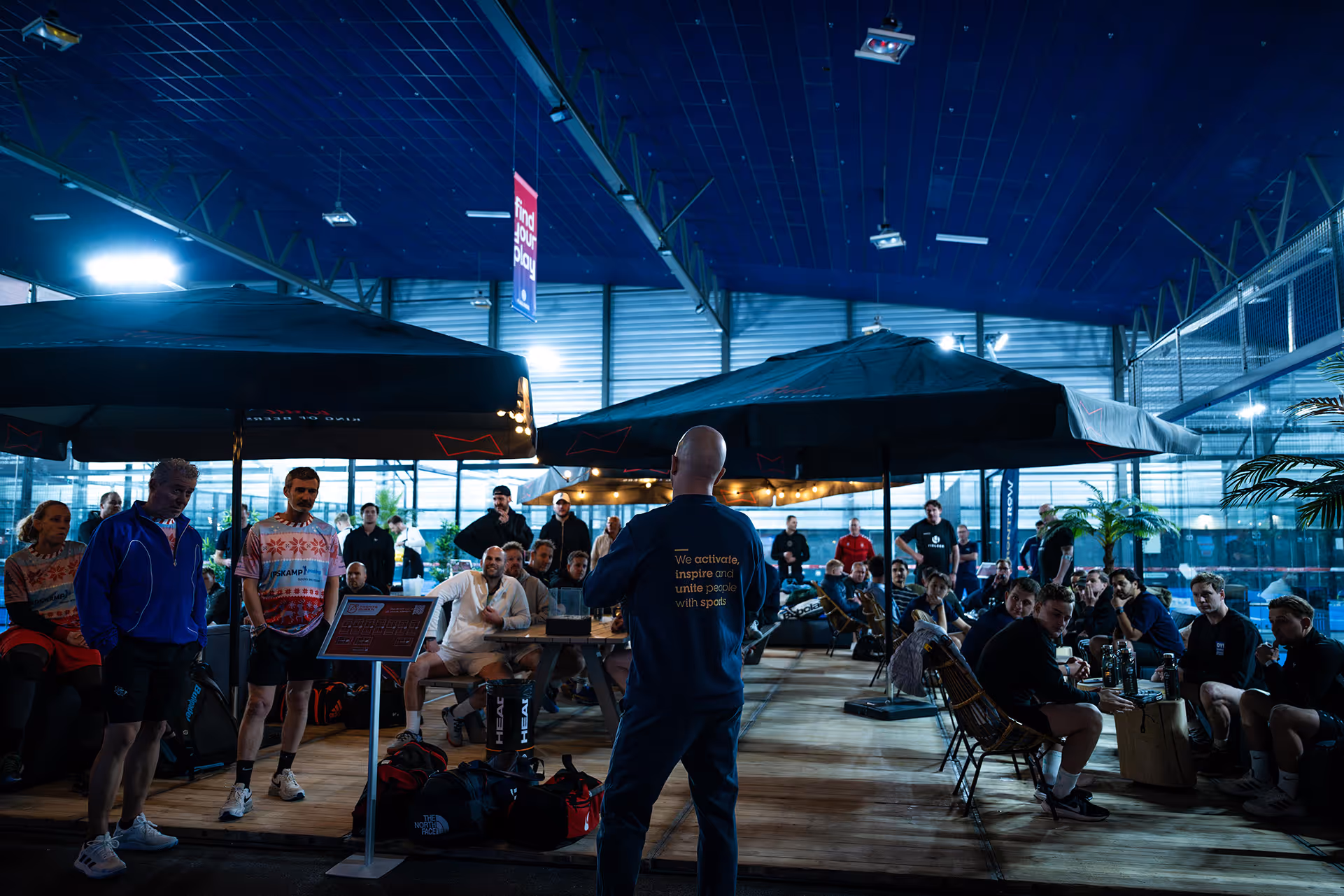 De oprichter van sportmarketingbureau FrontRow is voor een groep aan het spreken tijdens een B2B sportevenement op de padelbaan