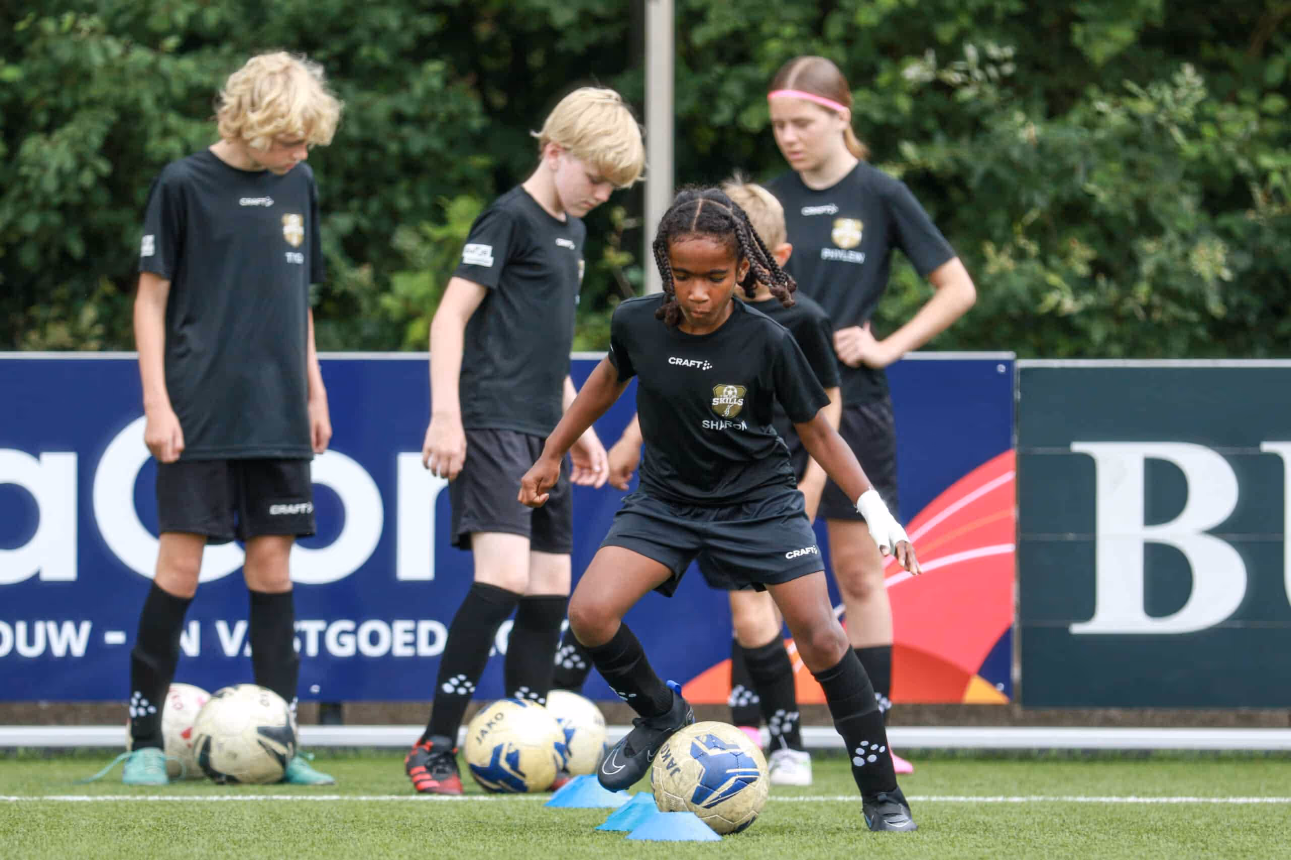 Een dribbelende deelnemer op het voetbalveld samen met andere kinderen tijdens een B2C sportevenement