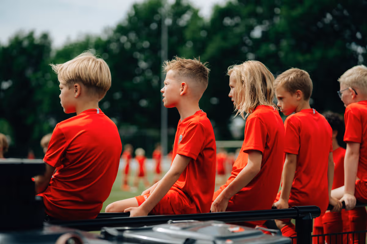 Een dribbelende deelnemer op het voetbalveld samen met andere kinderen tijdens een B2C sportevenement