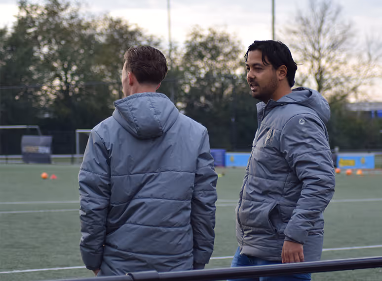 Twee mannen op een voetbalveld, die hun rol als sportprofessionals van FrontRow laten zien.