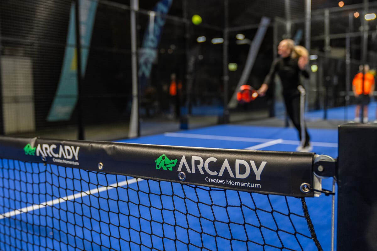 Padelbaan met het logo van Arcady op het net tijdens het zakelijke sportevent Kerst met Ballen