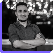 Icaro Vinícius Torres de braços cruzados com luzes no fundo. 
