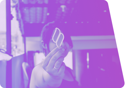 Imagem de uma mulher segurando um adesivo com o logo da Taller