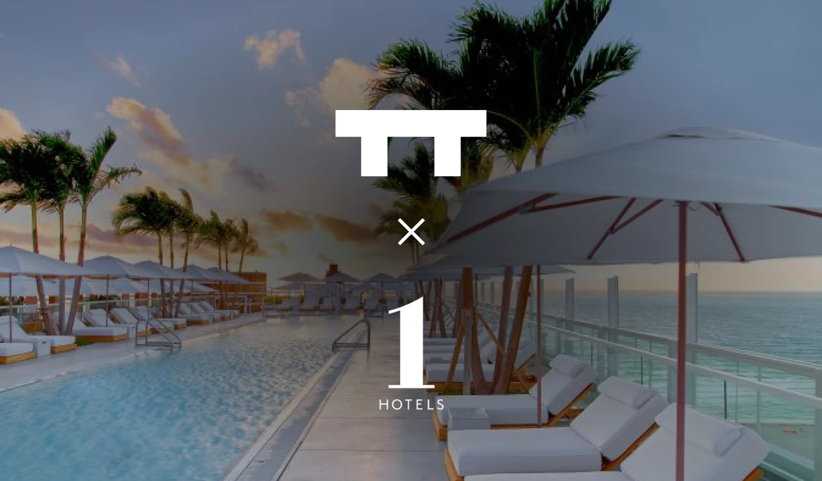 Oceanfront rooftop pool with white lounge chairs, umbrellas, and palm trees at sunset.