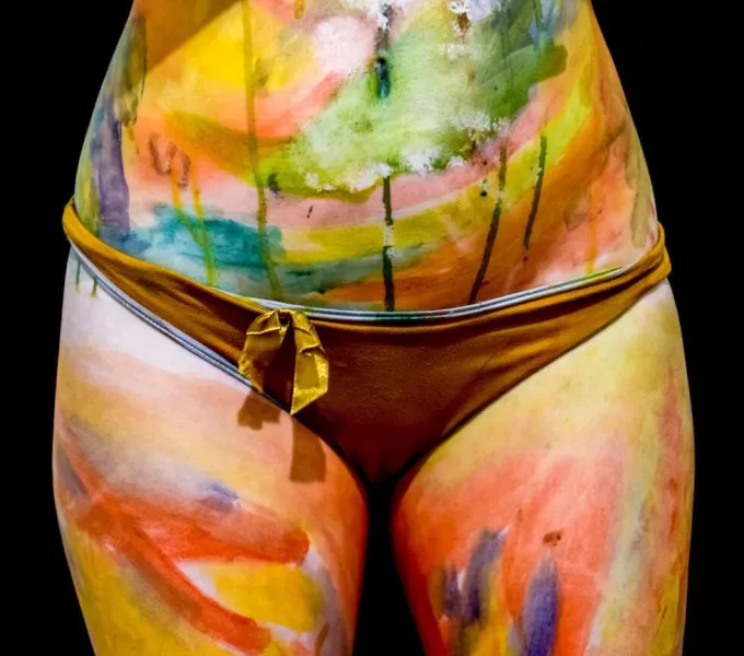 The midsection of a female body painted in beautiful colors to represent the sacral chakra and pelvic floor.