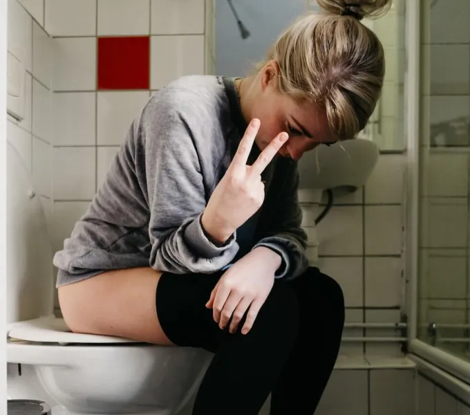 A woman sitting on the toilet, frustrated about her overactive bladder.