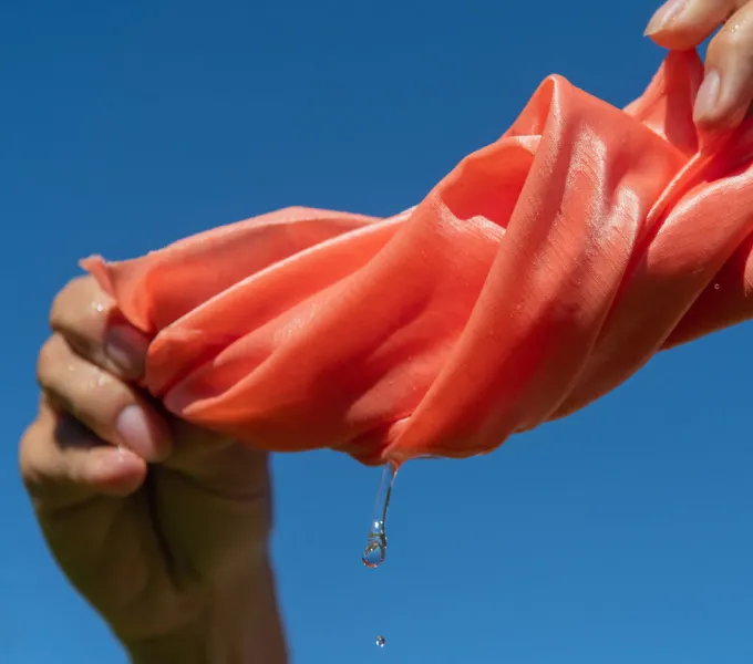 A woman wringing water out of a pink cloth.