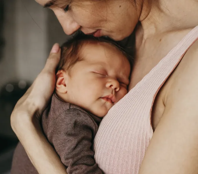 A content mother hugging her sweet, sleeping baby close to her chest.