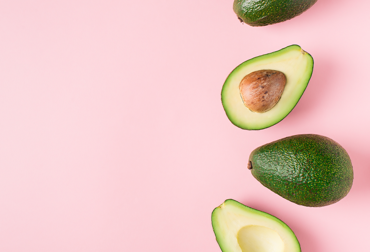 Avocados on a pink backdrop representing Diet to Gain Muscle Mass for women