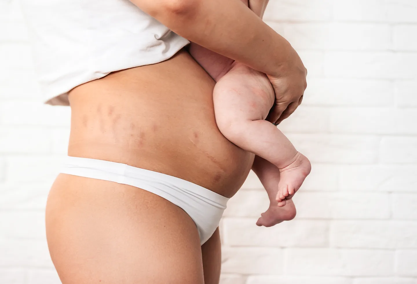 New mother holding her baby, representing the postpartum recovery milestones nobody talks about.