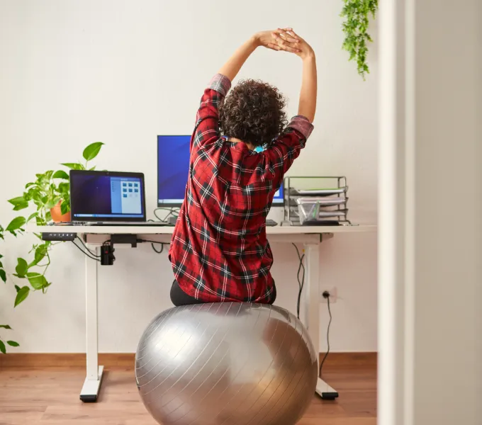 Woman sitting at her ergonomic workstation and doing exercises to support her physical and pelvic health. 