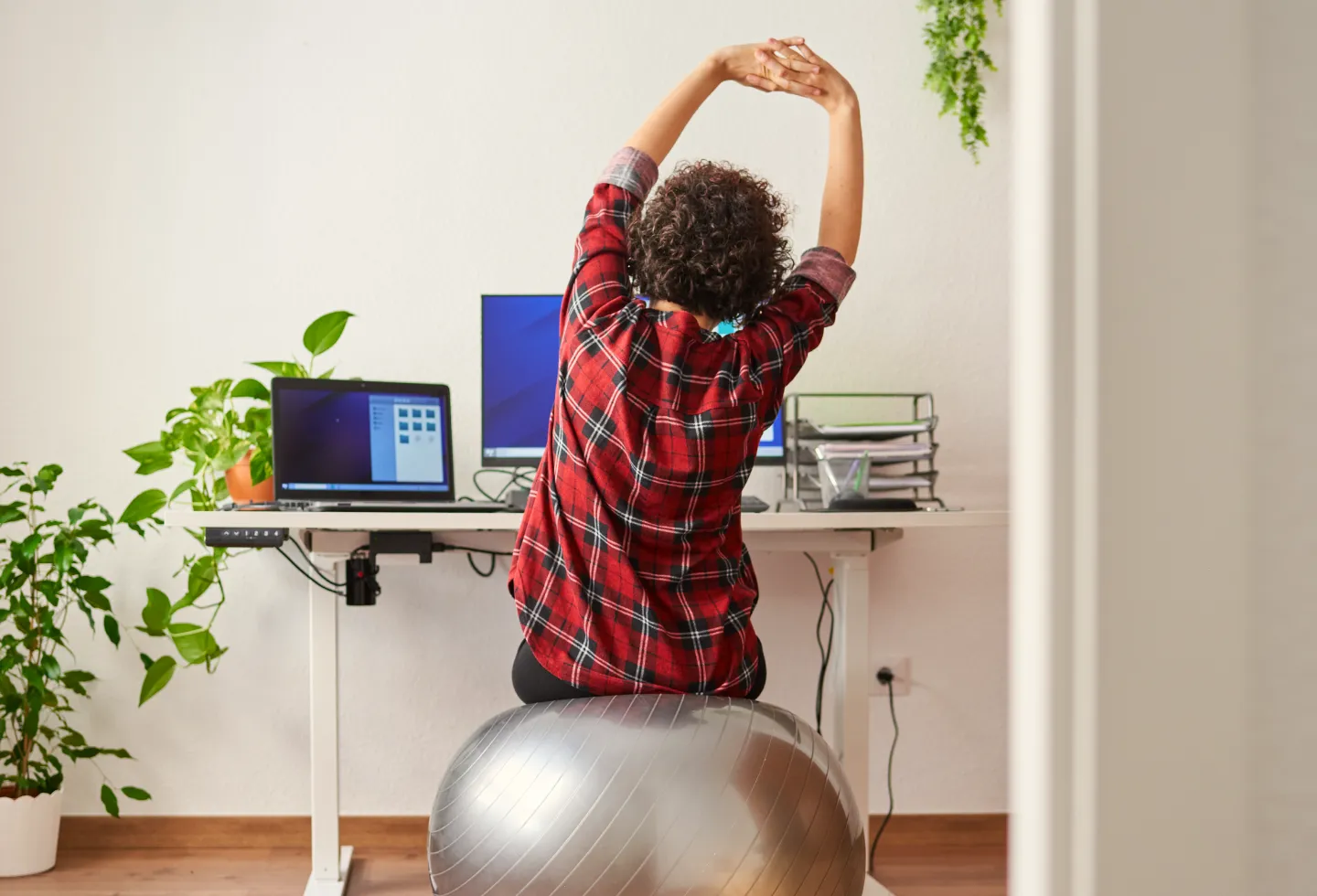 Woman sitting at her ergonomic workstation and doing exercises to support her physical and pelvic health. 