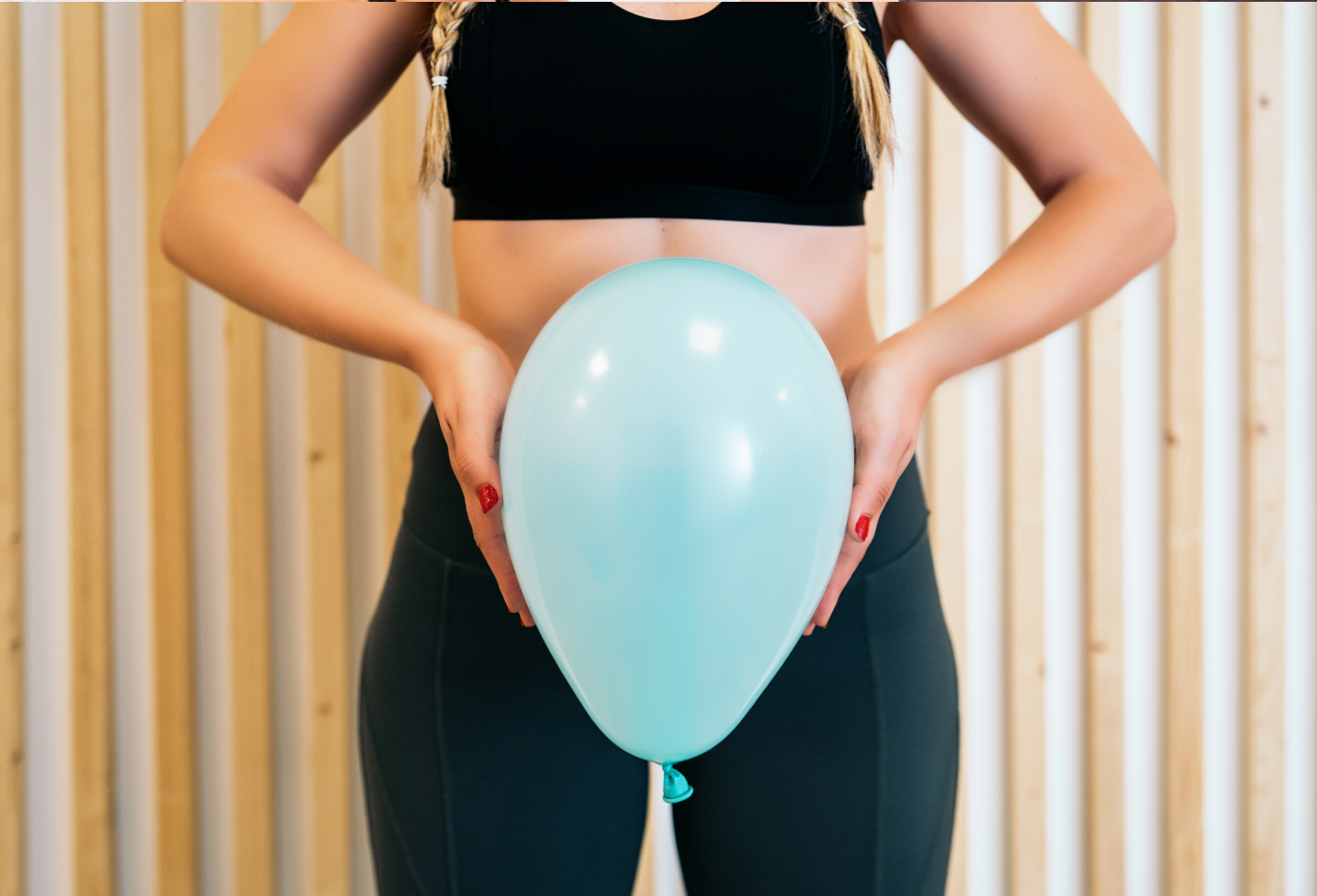 Woman holding inflated balloon in front of her pelvis, representing pelvic floor function what's normal and not normal