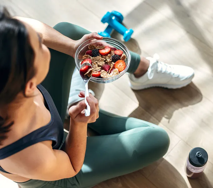 Woman in exercise clothes eating foods to help her joint health.