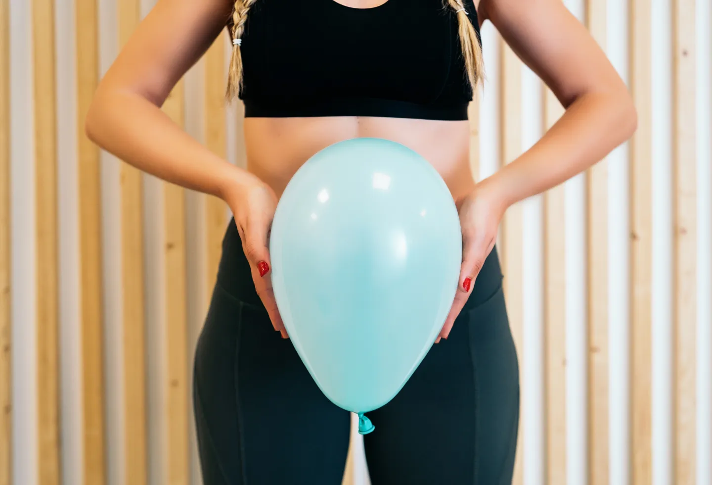 Woman holding inflated balloon in front of her pelvis, representing pelvic floor function what's normal and not normal.