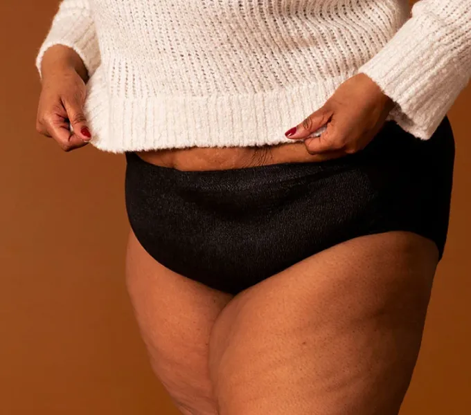 A woman wearing a pair of coral colored absorbant underwear.