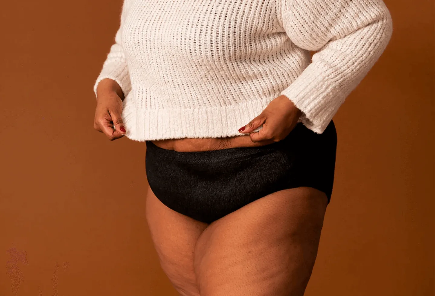 A woman wearing a pair of coral colored absorbant underwear.