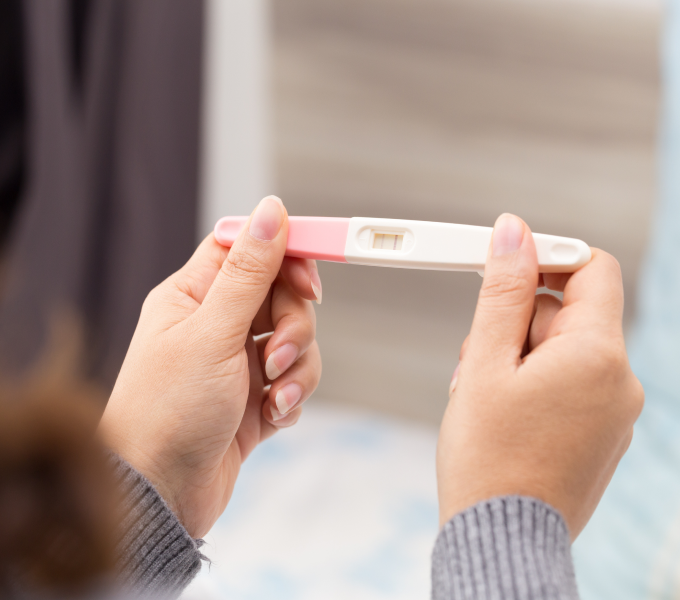 Woman trying to conceive holding pregnancy test representing a guide to preparing to conceive