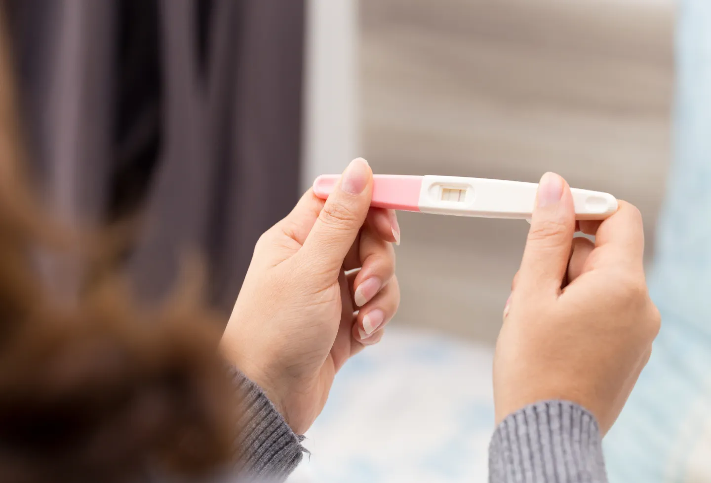 Woman trying to conceive holding pregnancy test representing a guide to preparing to conceive.