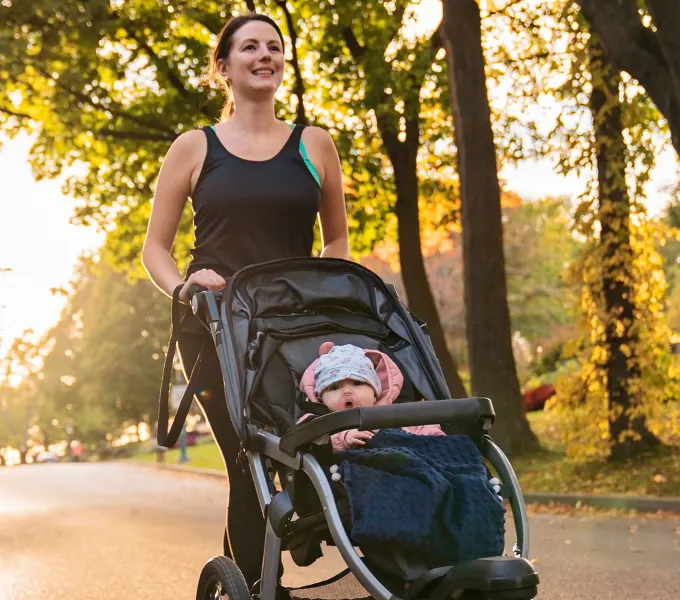 Woman returning to running postpartum after pelvic floor therapy, on a run with her baby in a jogger.