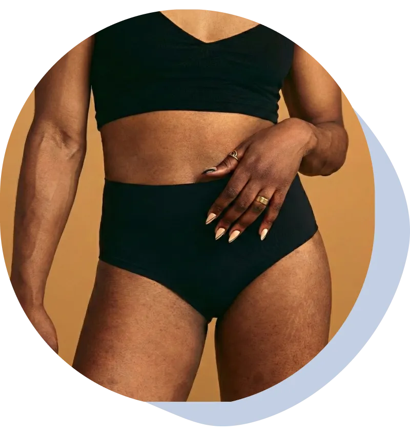 A close-up of a woman in green underwear, standing with her arms behind her back.