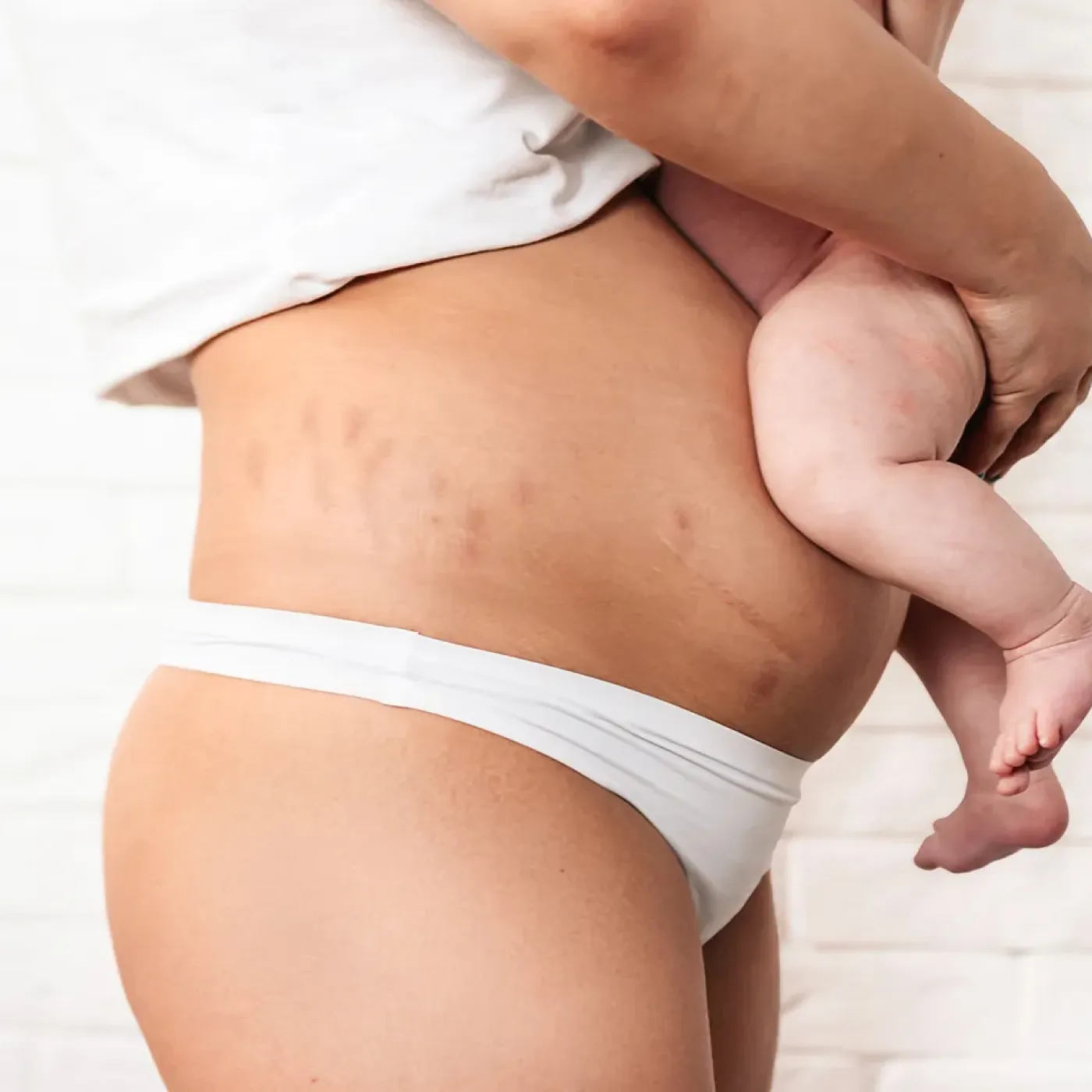 New mother holding her baby, representing the postpartum recovery milestones nobody talks about.