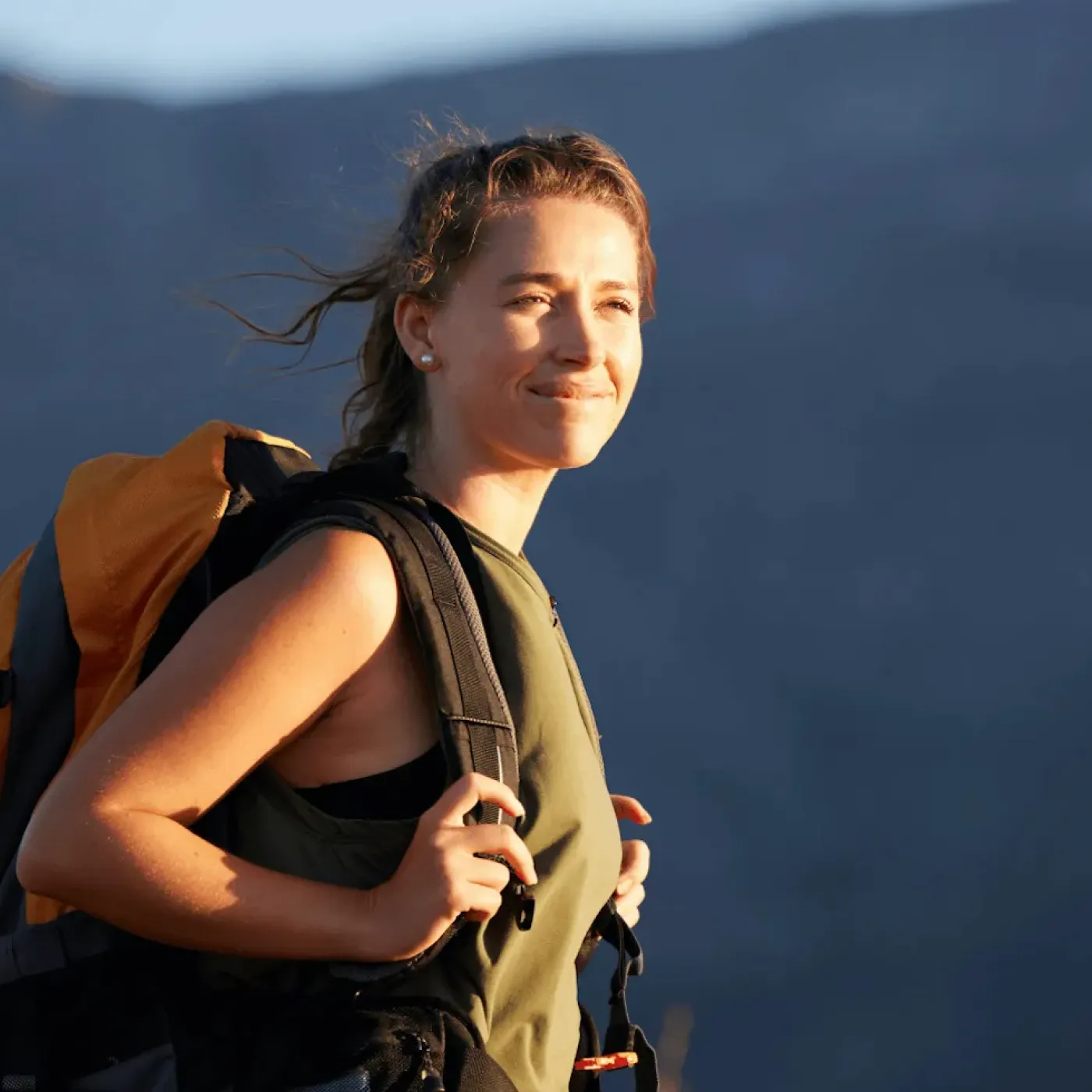 Content woman wearing a backpack outdoors, representing comfort with travel and pelvic health.