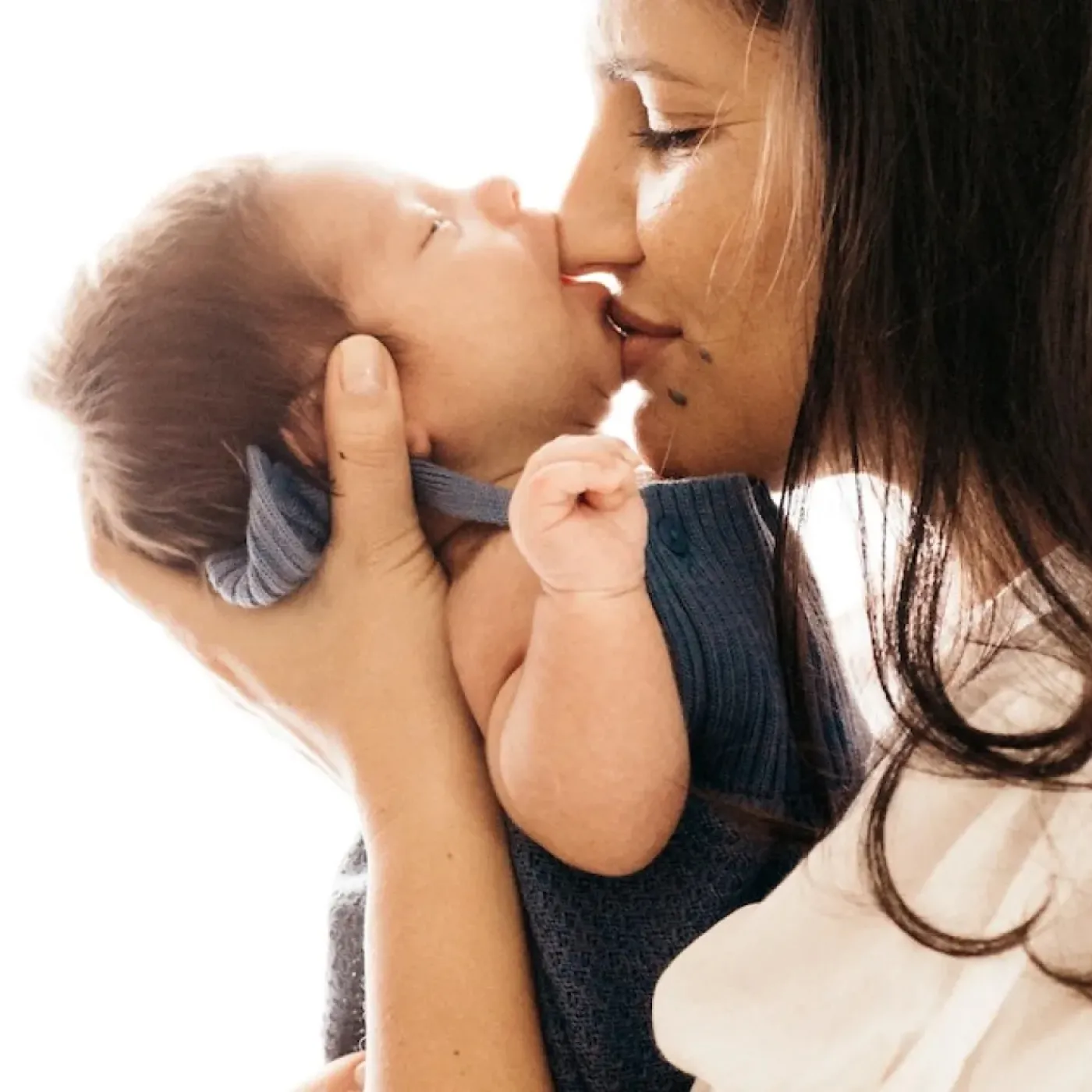 A woman suffering from mommy's wrist supports her baby's head with her hand while baby kisses her on the nose.