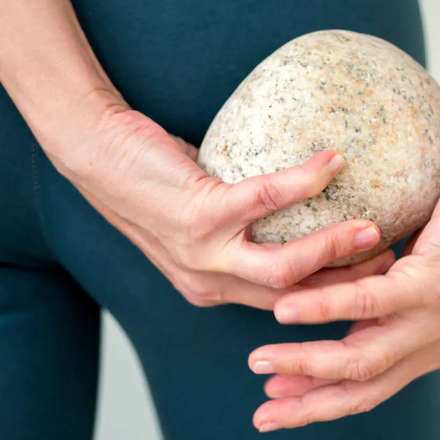 A woman holding a large stone behind her body for as story on what pelvic organ prolapse feels like.