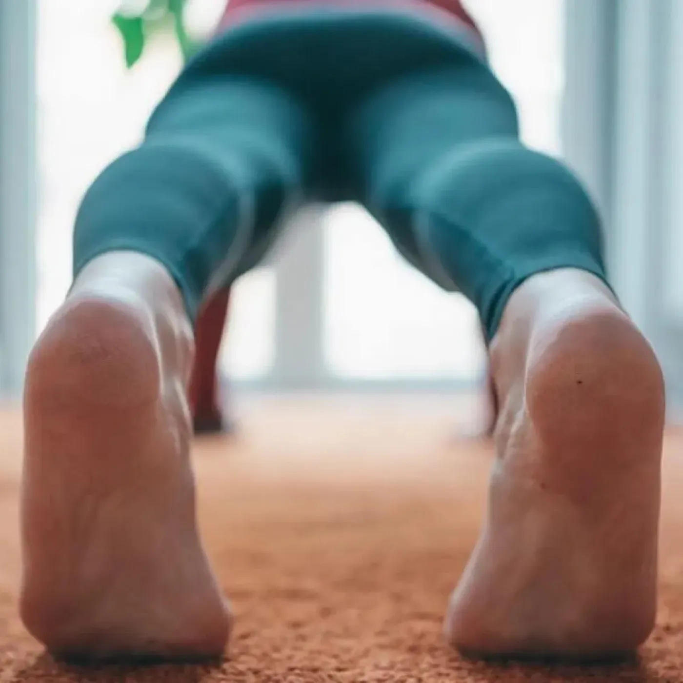 A photo of a woman in plank position, shot from behind to highlight her tight or hypertonic pelvic floor.