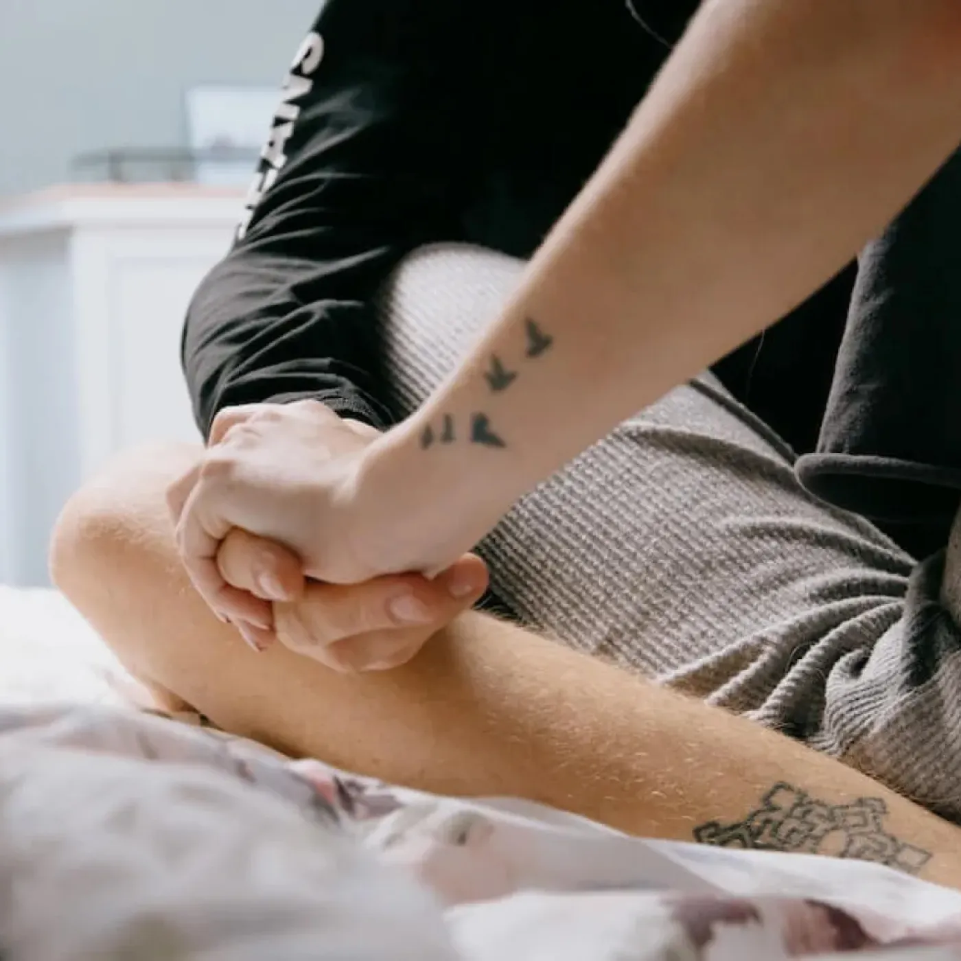 A couple sitting on a bed, holding hands.