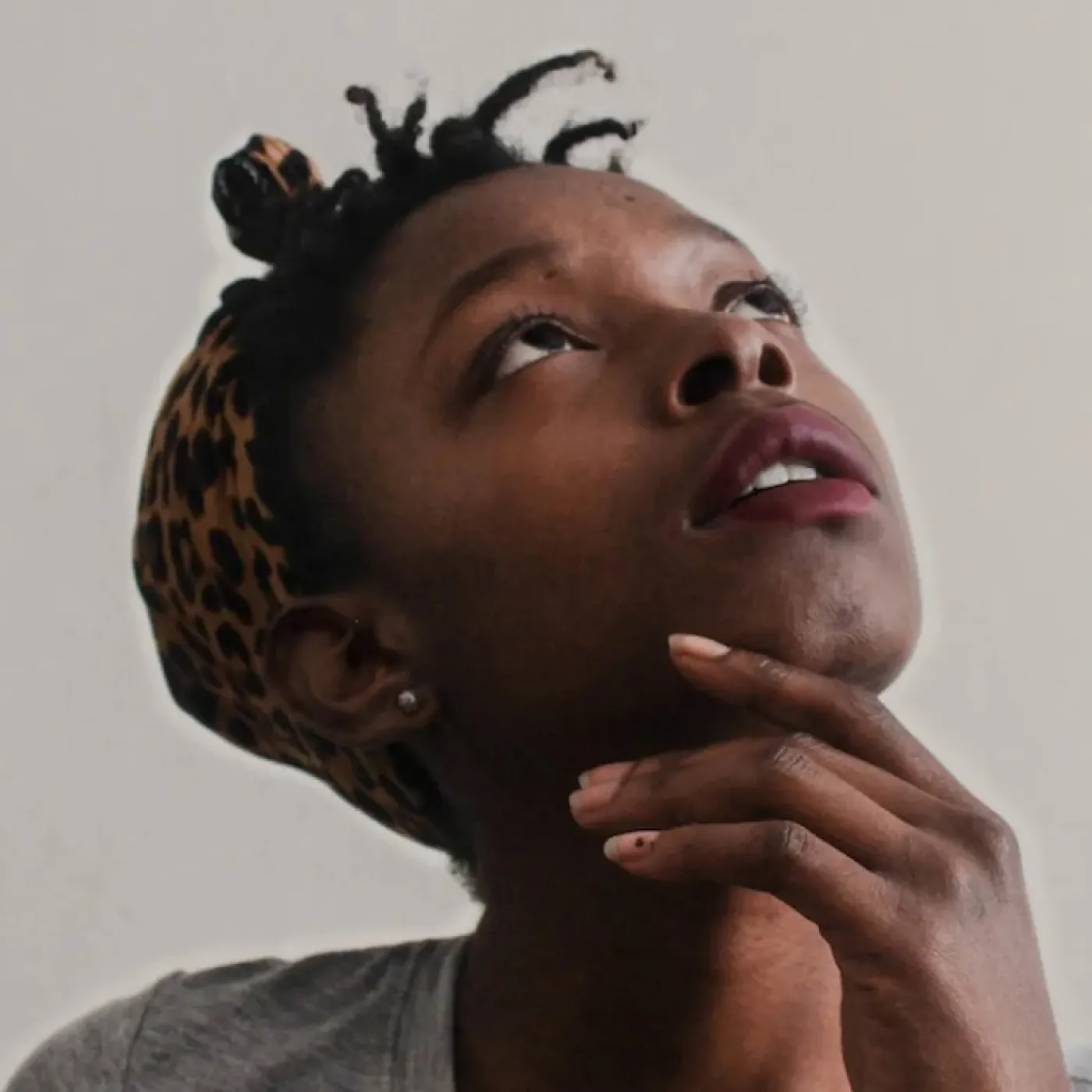 A young woman looking up with her hand on her chin, showing curiosity about her pelvic floor exam.
