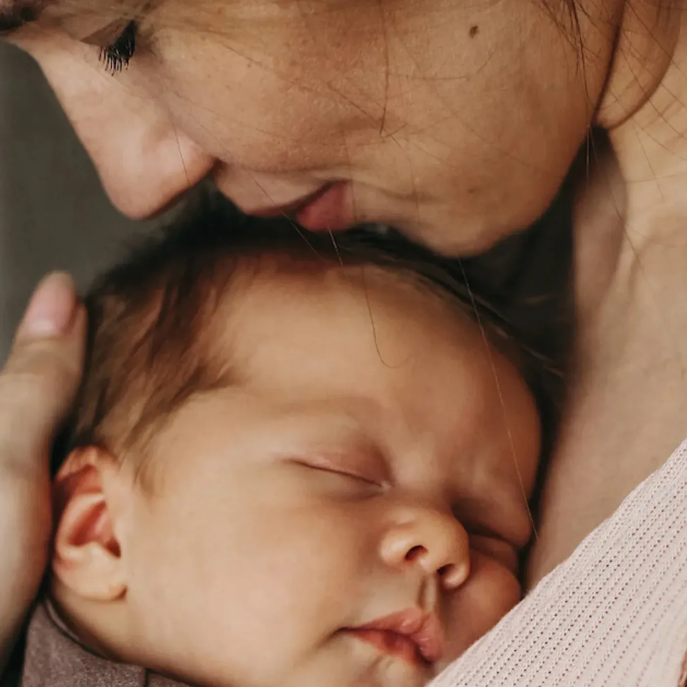 A content mother hugging her sweet, sleeping baby close to her chest.
