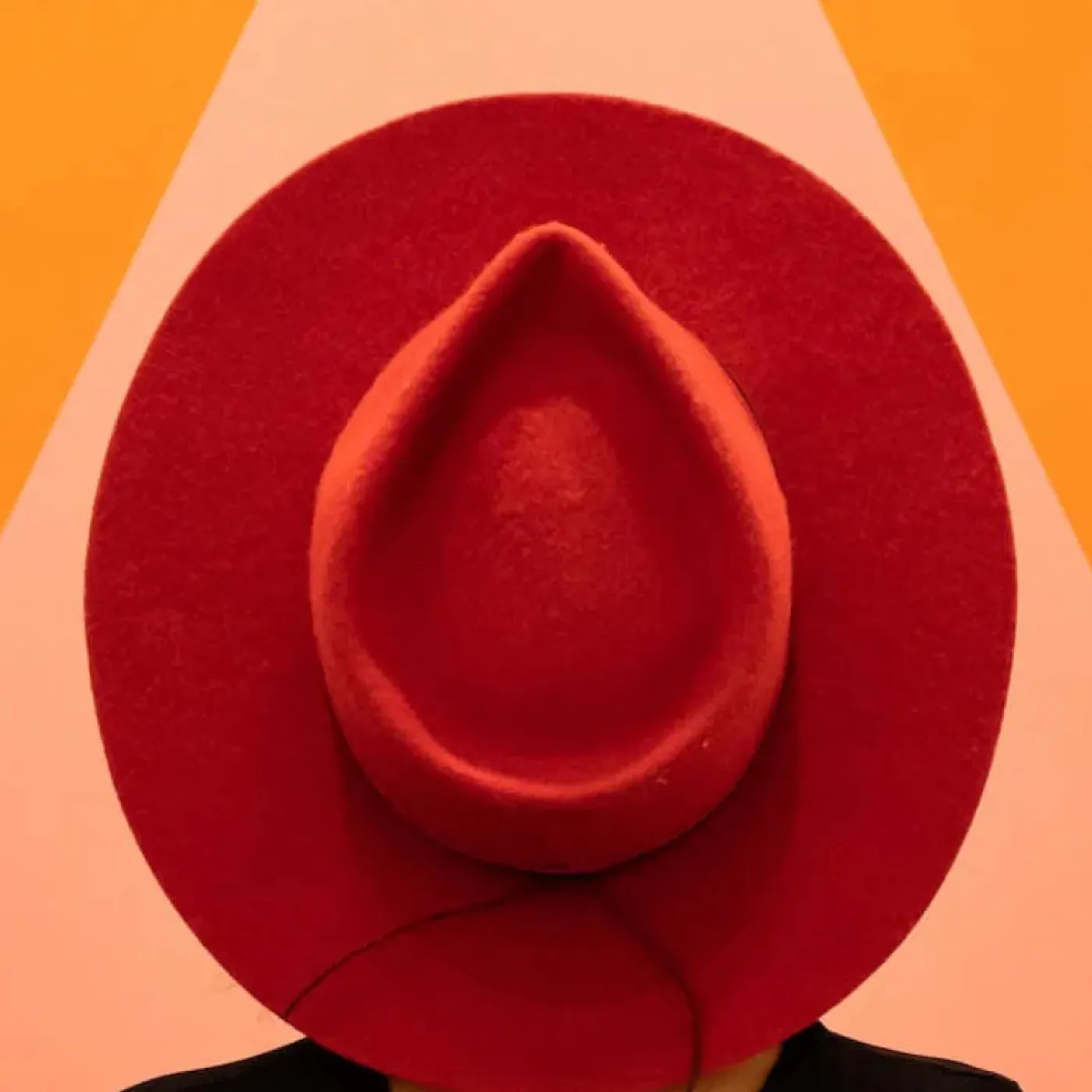A photo of a woman wearing a red hat in front of a big triangle to symbolize vaginal pain.