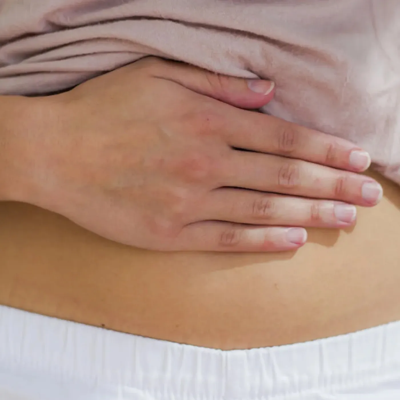 A woman concerned about diastasis recti holding her hand on her abdominals.