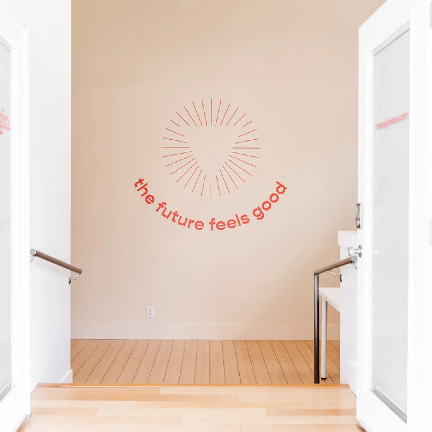 The open doors of Origin’s Sugar Land clinic frame wall art featuring the words “the future feels good”.