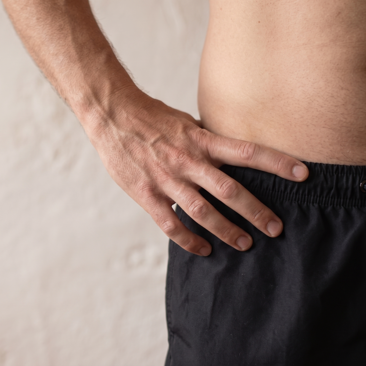 Zoomed in photo of man with a hand on hip, representing male pelvic health: male pelvic floor dysfunction, common symptoms, and how pelvic floor physical therapy