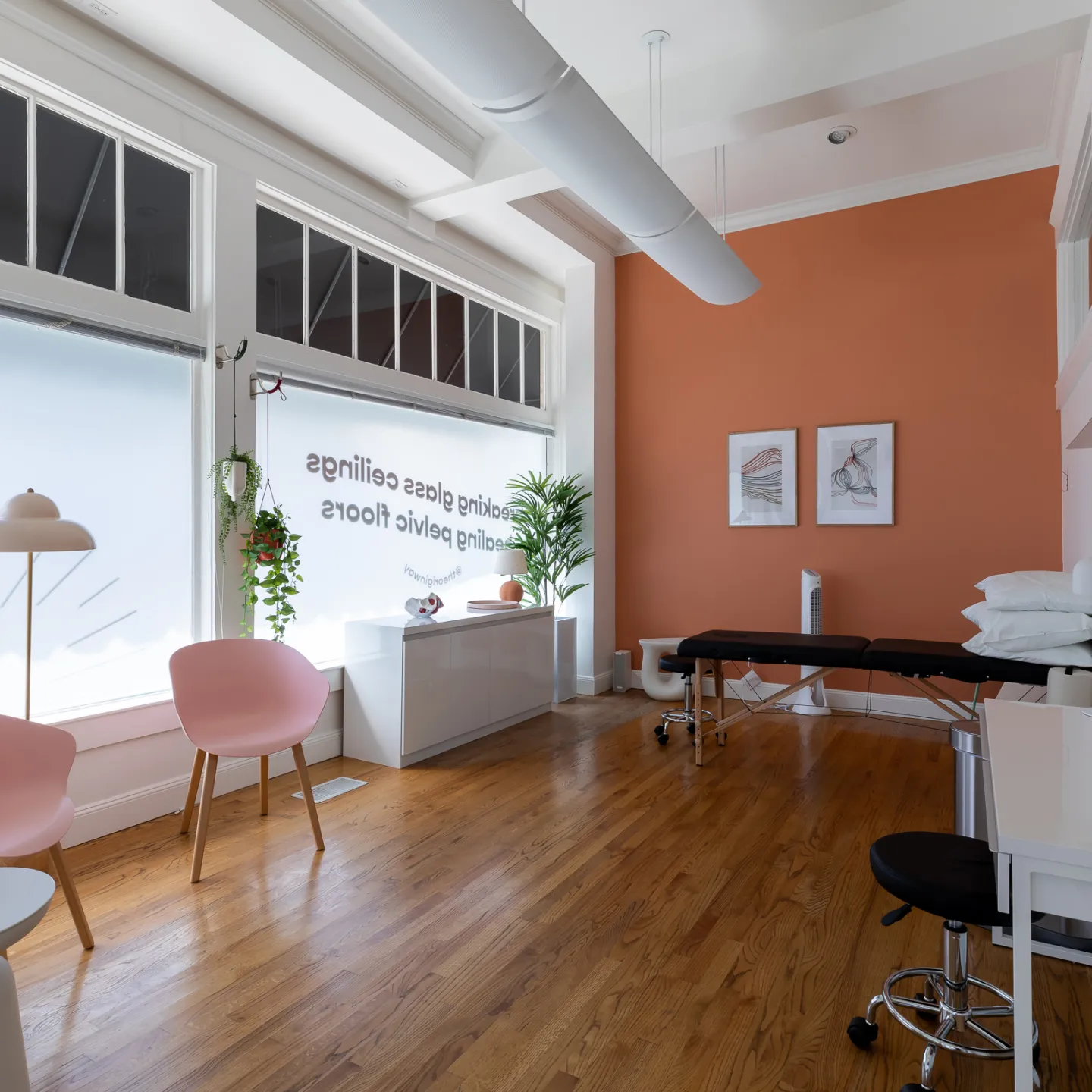 A room in Origin clinic featuring a table, several chairs, and a window allowing natural light to enter.