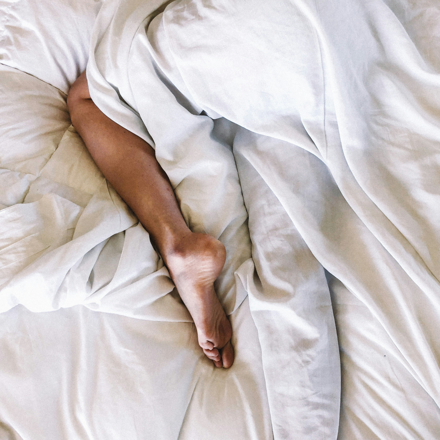 Image of person's legs laying in bed, representing painful sex